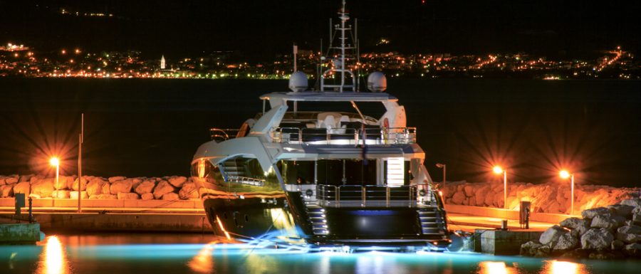 Luxury motor yacht moored to pier at night